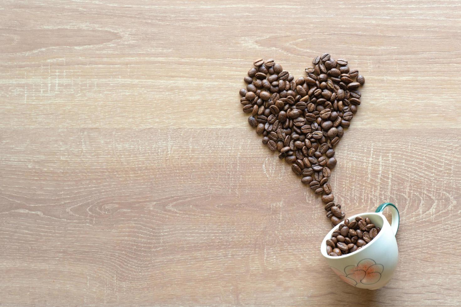 molti chicchi di caffè tostati a forma di cuore con una tazza di ceramica foto