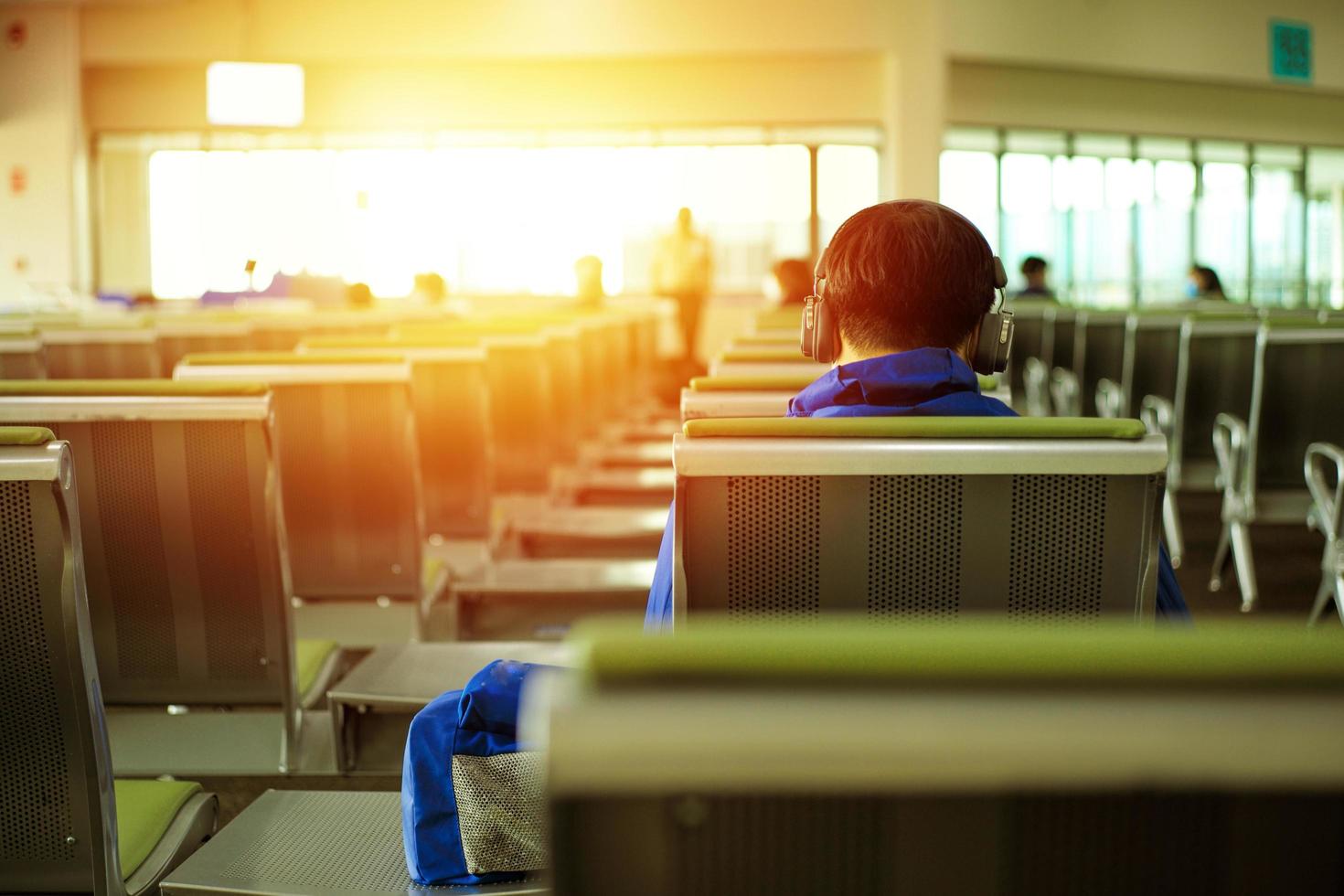 indietro ritratto di un uomo che ascolta la musica con un auricolare in attesa del volo nella sala del terminal delle partenze foto