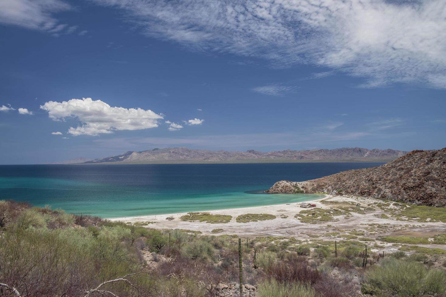 mare azzurro con montagne e cielo azzurro con nuvole nella penisola di baja baja california sur punta armenta, messico foto