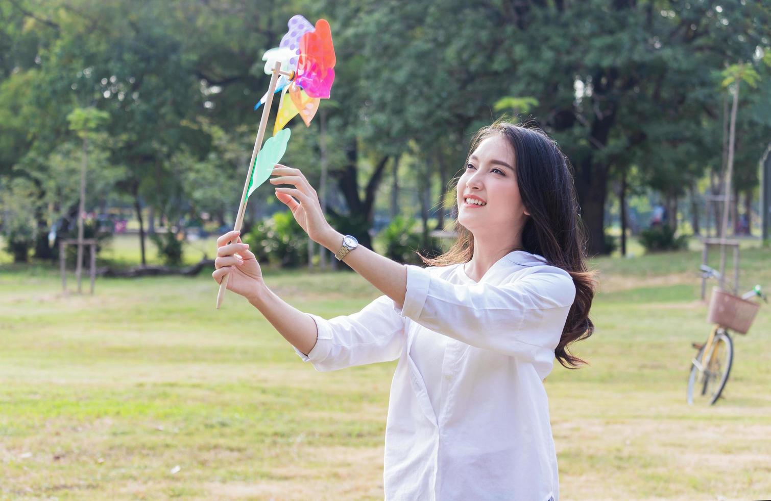 bella donna asiatica che gioca con le turbine nel parco felicemente. concetto di vivere una vacanza felice foto