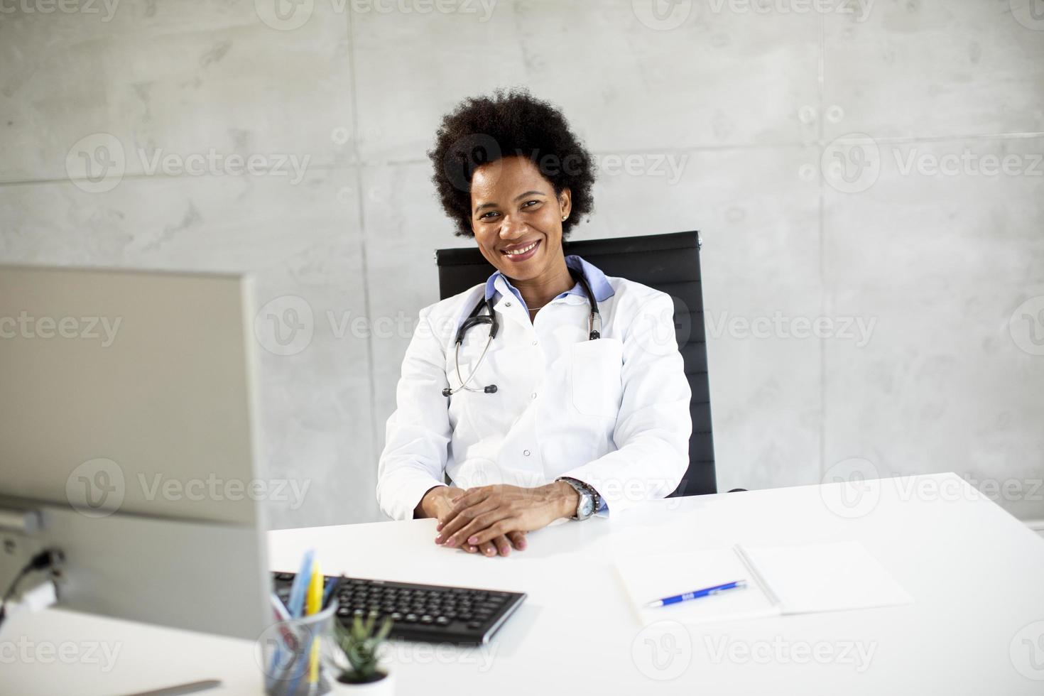 medico indossa camice bianco dietro la scrivania in ufficio foto