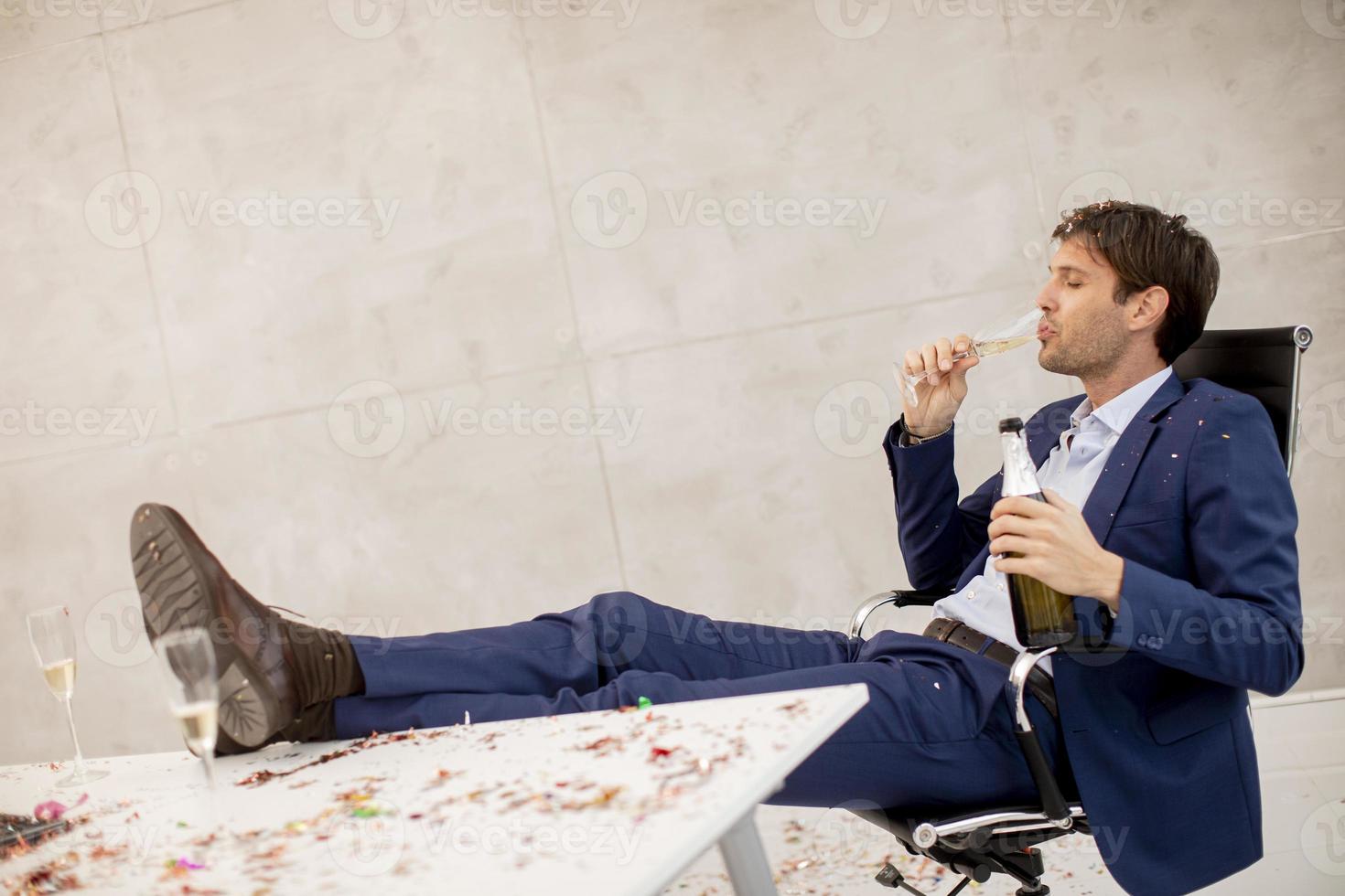 uomo che beve champagne con i piedi in alto foto