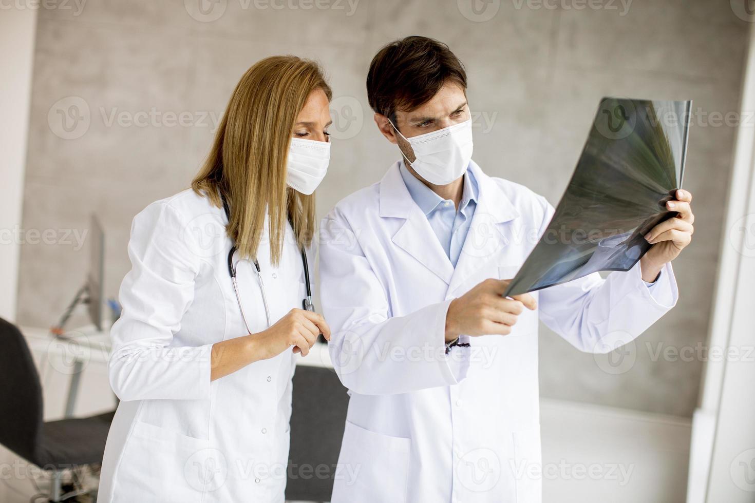primo piano dei medici mascherati che esaminano una radiografia foto