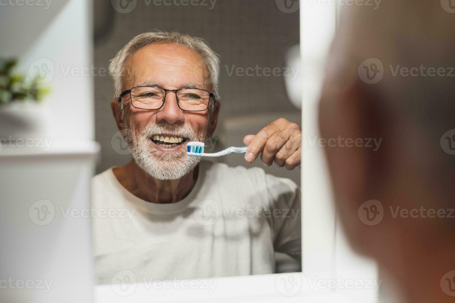 un' anziano uomo spazzole il suo denti foto