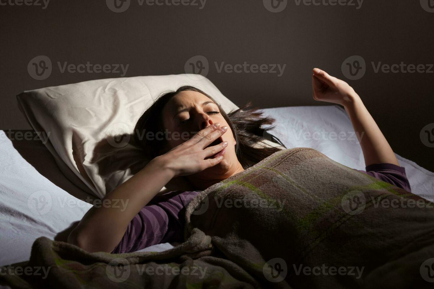 un' giovane donna riposo nel il letto foto