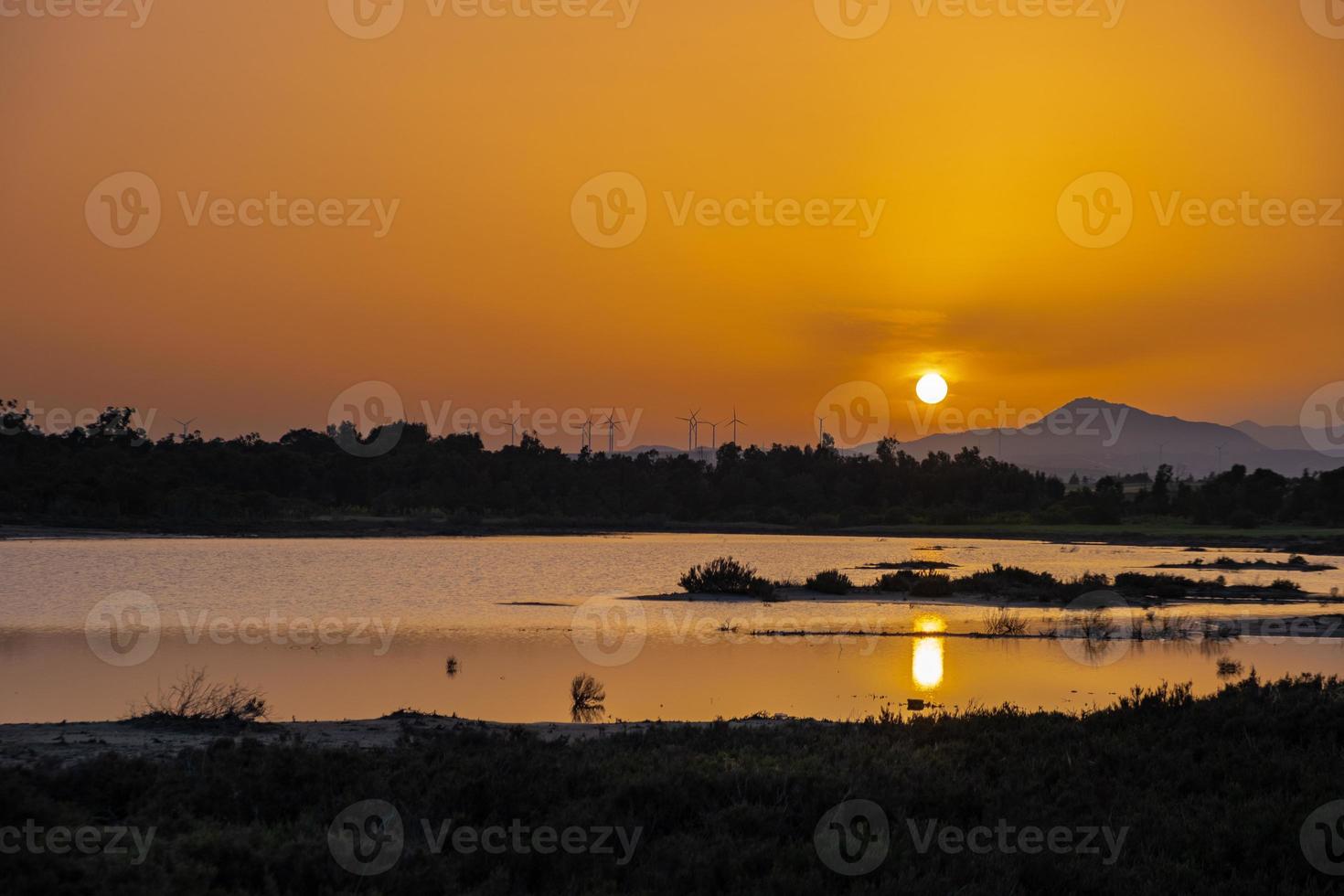 tramonto al lago salato di Larnaca con il sole al tramonto e le turbine eoliche in lontananza foto