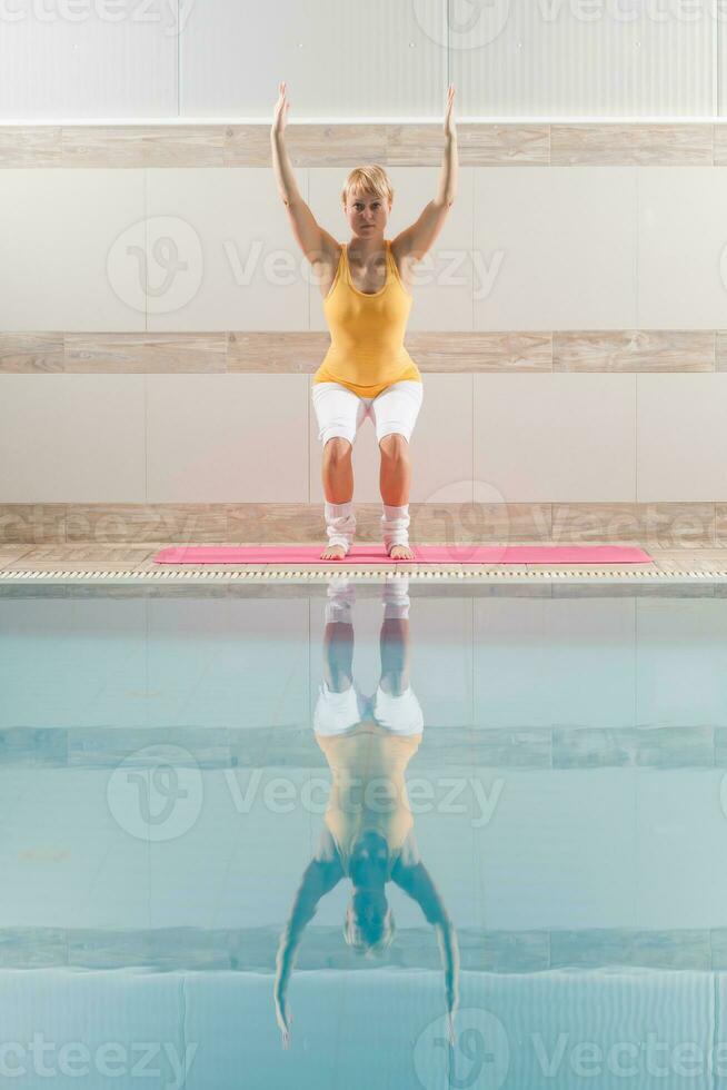 un' donna fare fisico esercizi a il nuoto piscina foto