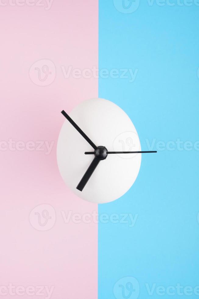 un orologio a forma di uovo su sfondo blu e rosa foto