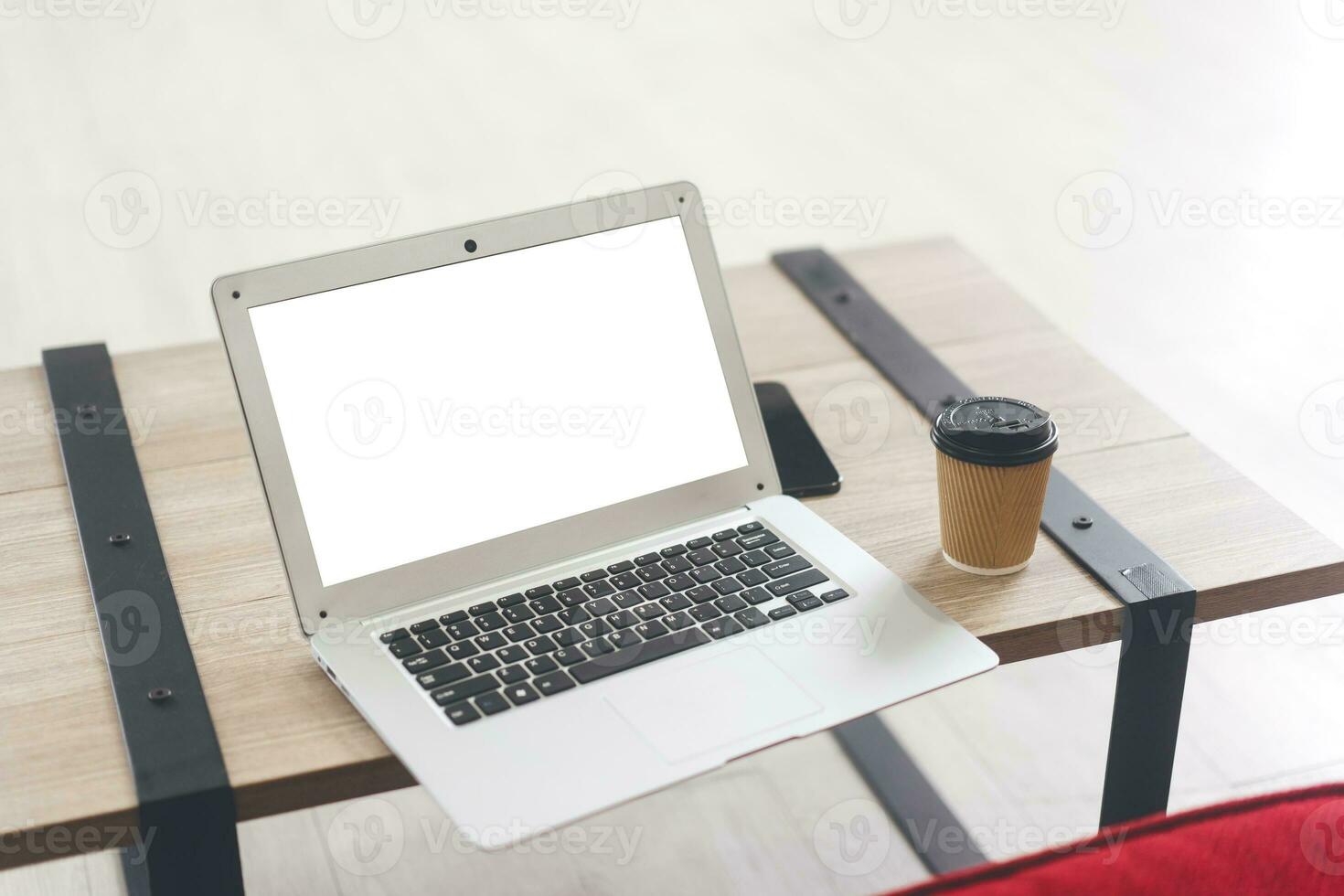 modello il computer portatile computer con vuoto bianca schermo su piccolo tavolo con caffè carta tazza. foto