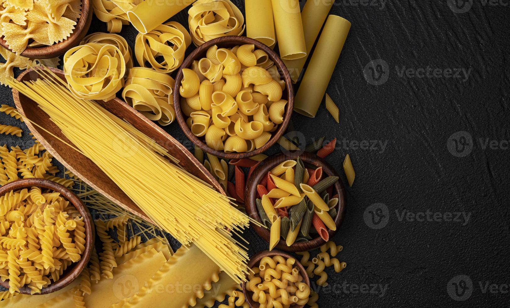 diversi tipi di pasta su sfondo nero con copia spazio per il testo foto