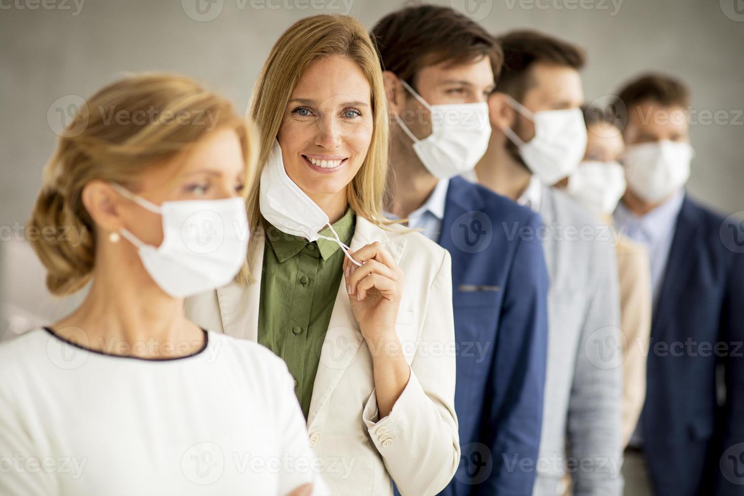 professionisti in fila con la donna che si toglie la maschera facciale foto