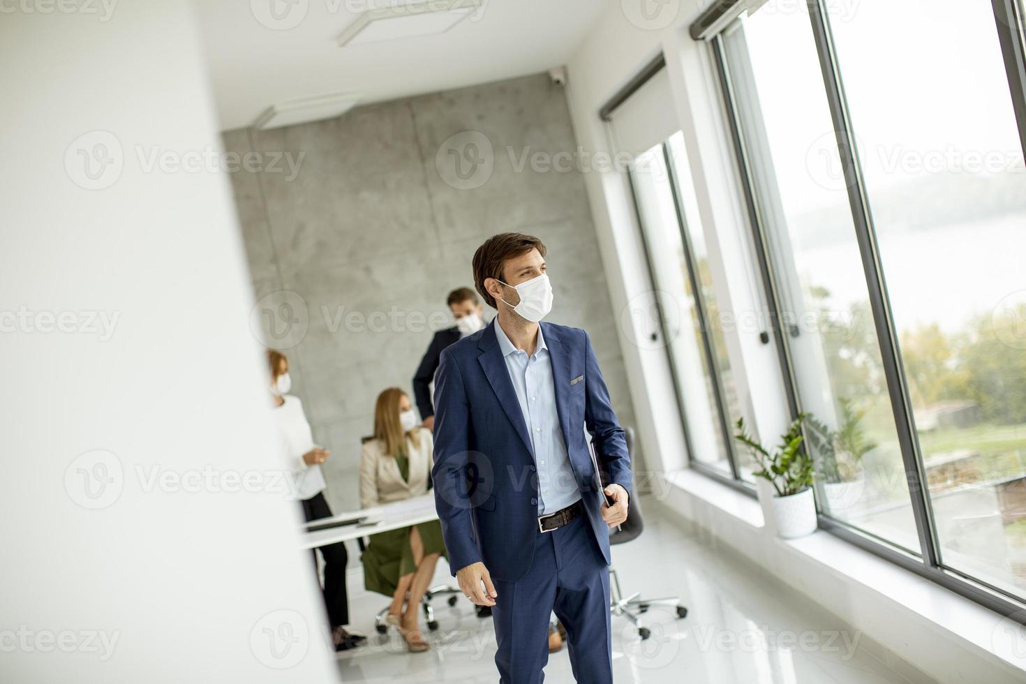 uomo che cammina in un ufficio con una maschera foto
