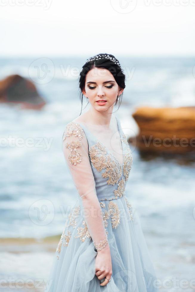 sposa in un vestito di luce blu che cammina lungo l'oceano foto