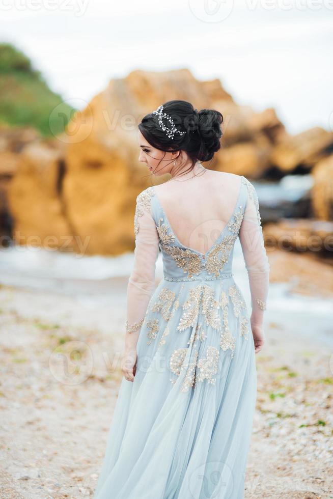 sposa in un vestito di luce blu che cammina lungo l'oceano foto