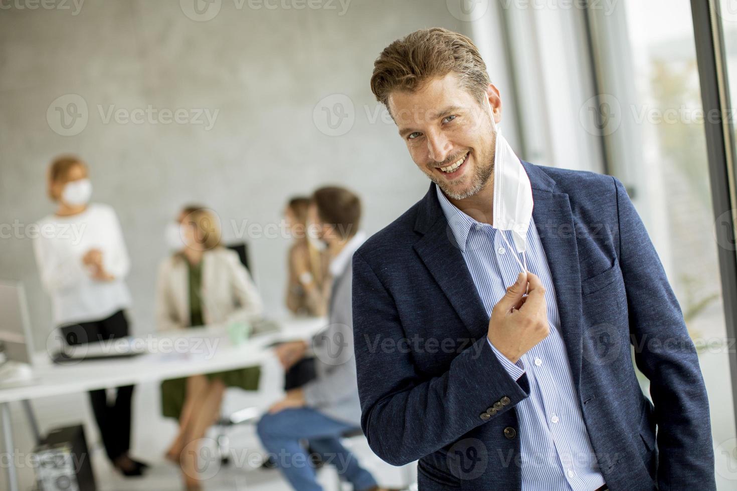 uomo d'affari sorridente che toglie la maschera foto