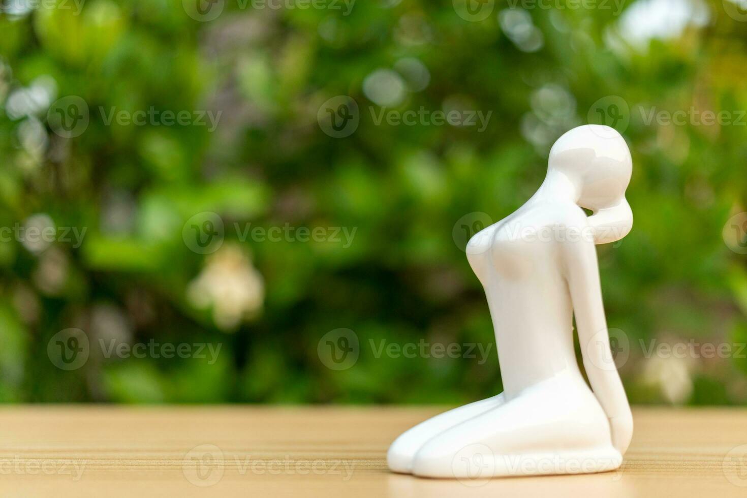 ceramica yoga figurina di donna fare yoga posa su di legno pavimento e verde foglia sfondo foto