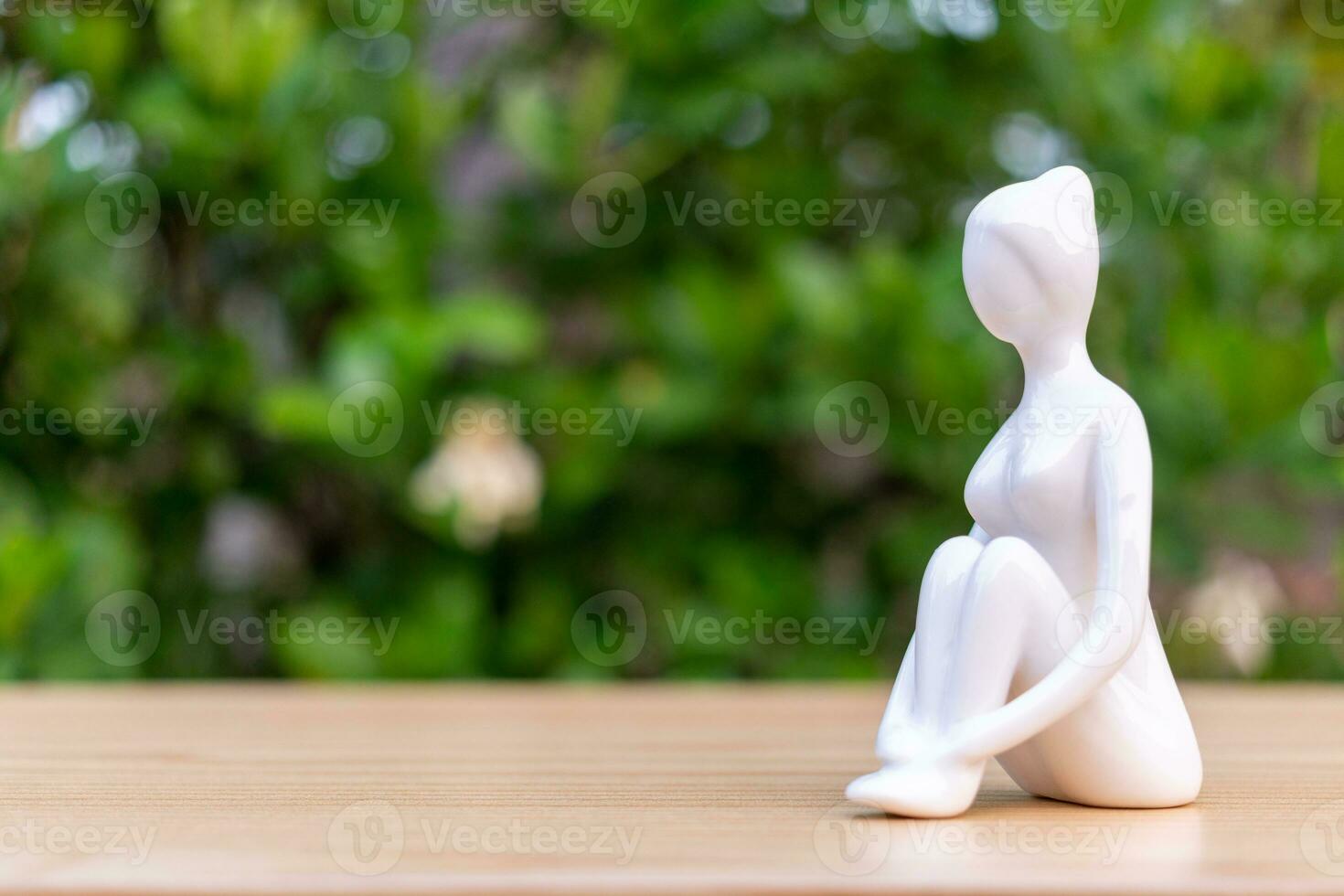 ceramica yoga figurina di donna fare yoga posa su di legno pavimento e verde foglia sfondo foto