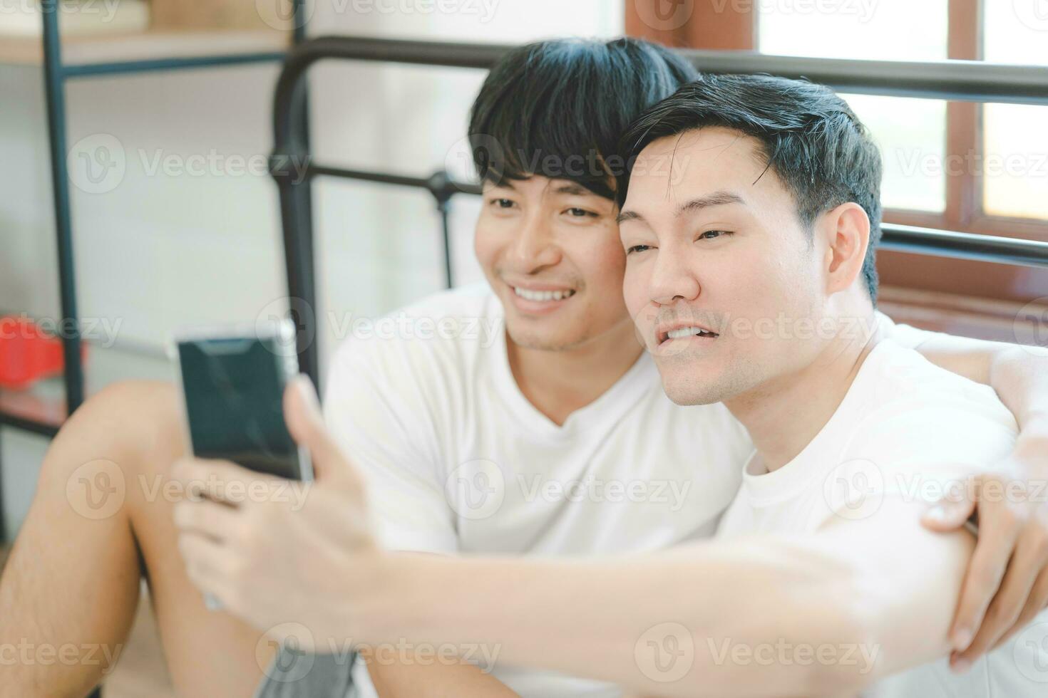 contento asiatico gay coppia uso mobile Telefono video chiamata o autoscatto su letto, LGBTQ concetto. contento gay coppia avendo divertimento utilizzando mobile smartphone nel letto. diversità di lgbt relazioni. foto