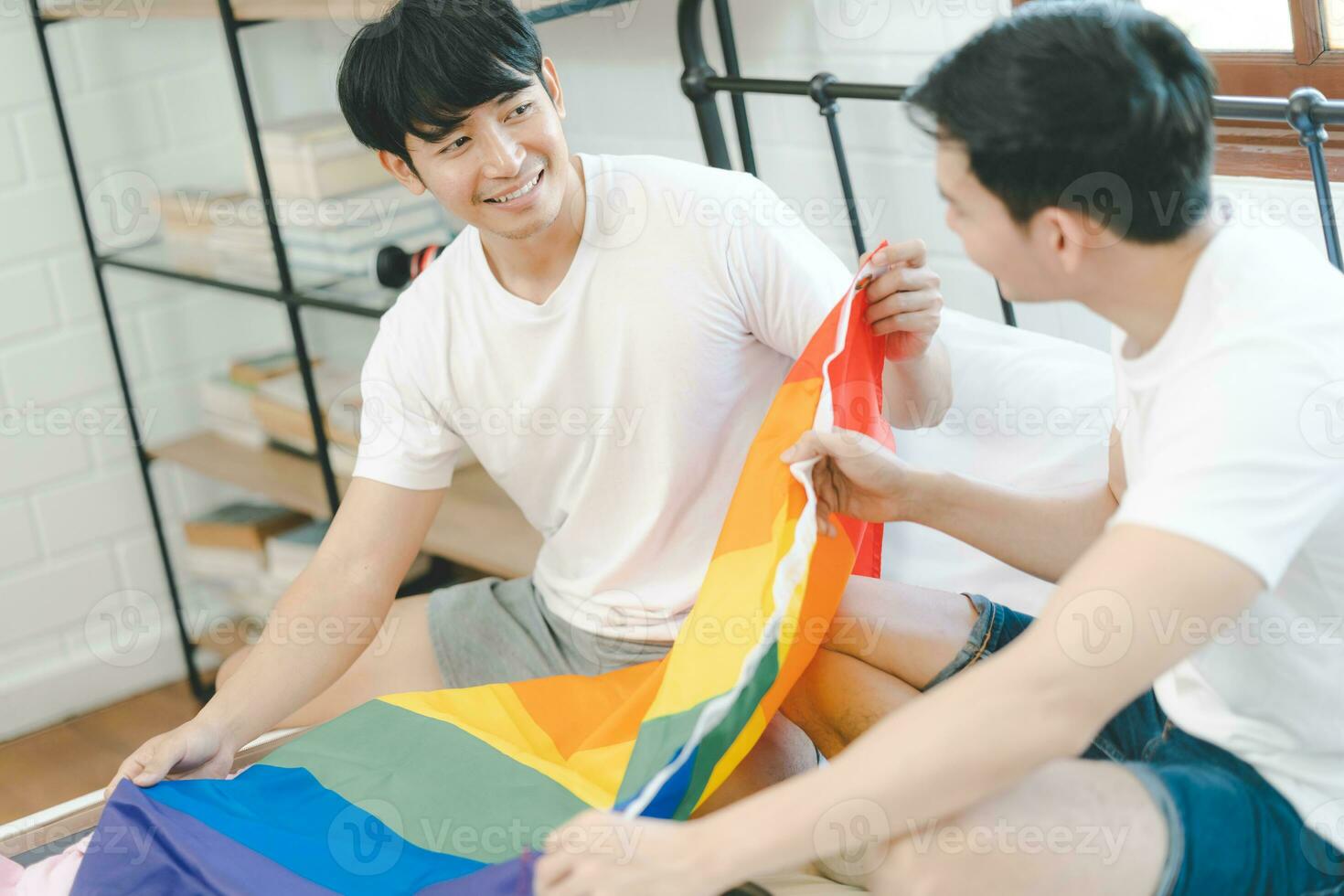 contento asiatico gay coppia Imballaggio valigia per viaggio preparazione per orgoglio mese. diverso gay coppia sedersi su letto Imballaggio bagaglio. arcobaleno bandiera. coppia di gay turisti. foto