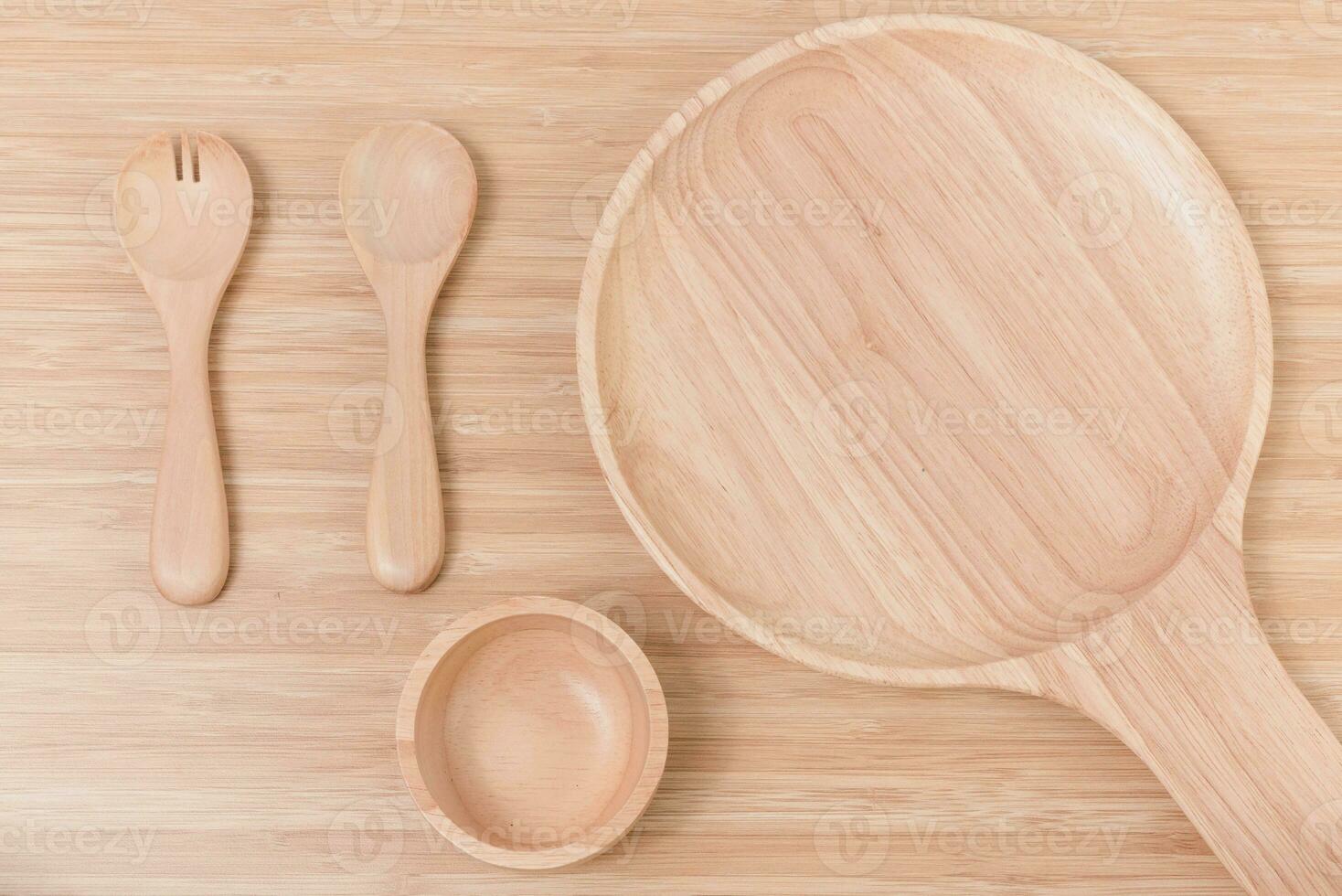 impostato di forchetta, cucchiaio e piatto legna su di legno tavolo foto