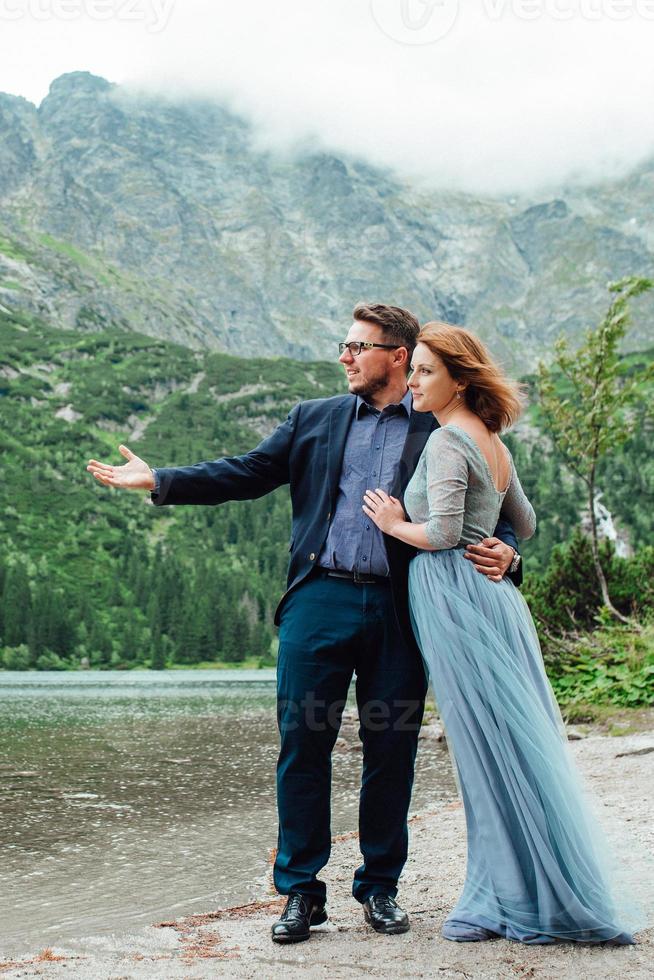 giovane coppia in una passeggiata vicino al lago circondato dalle montagne foto