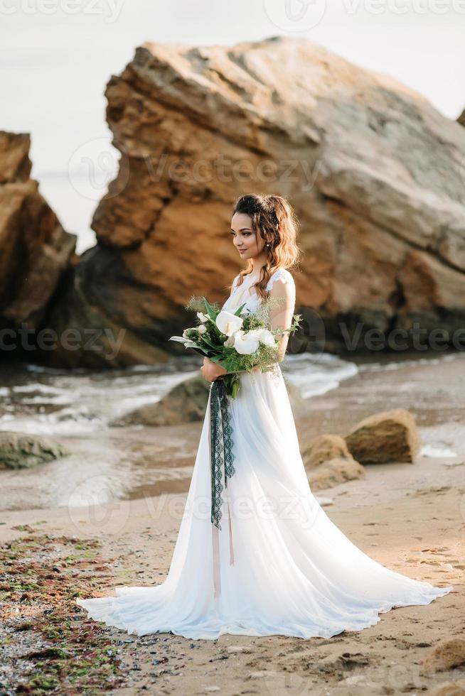 sposa con un bouquet da sposa sulla riva foto