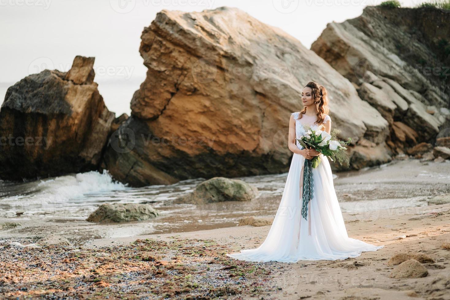 sposa con un bouquet da sposa sulla riva foto