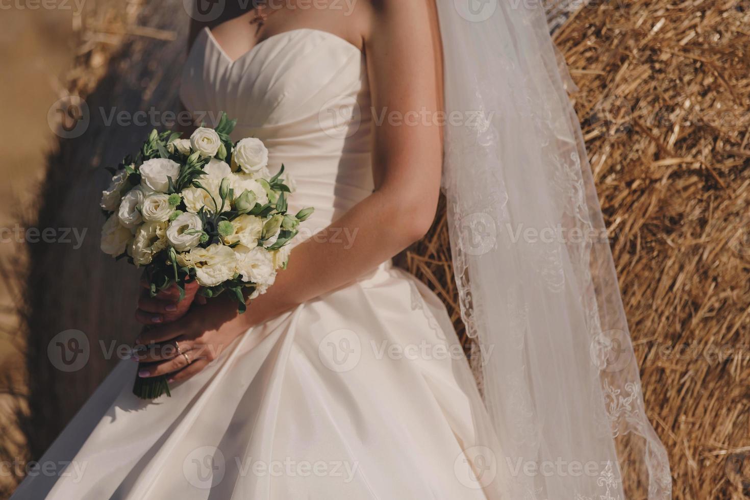 la sposa in un abito da sposa elegante detiene un bellissimo bouquet foto