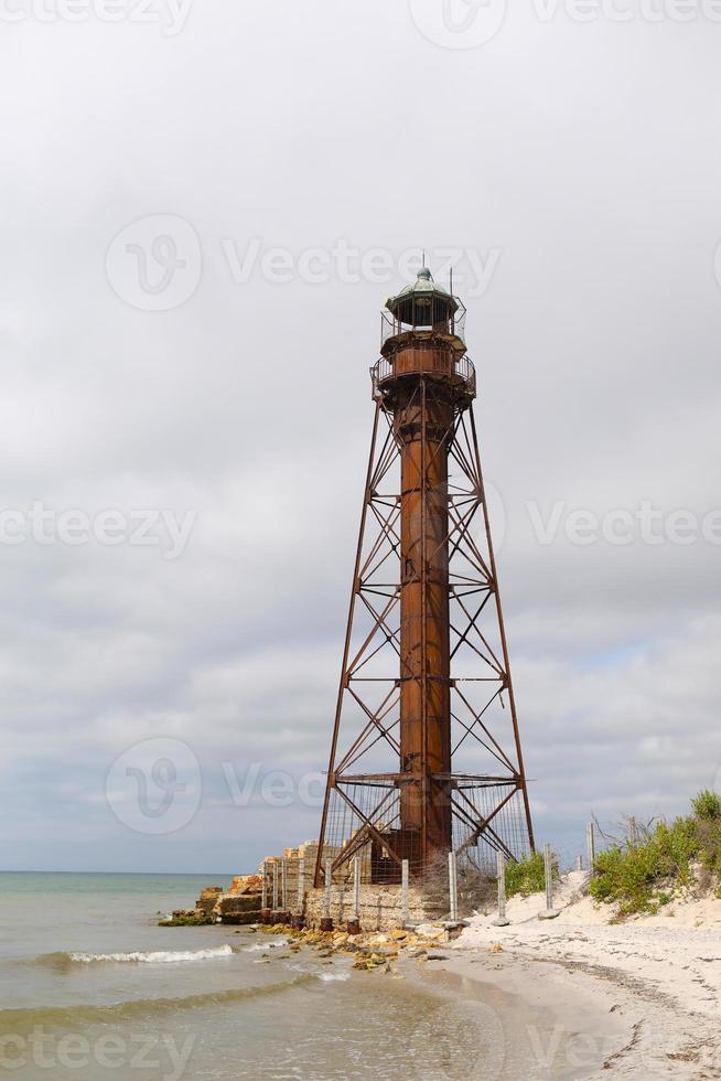 faro sulla riva sabbiosa con erba del mar nero foto