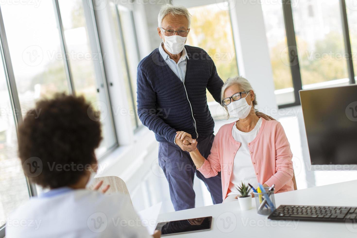coppia sposata matura presso l'ufficio del medico che indossa maschere foto