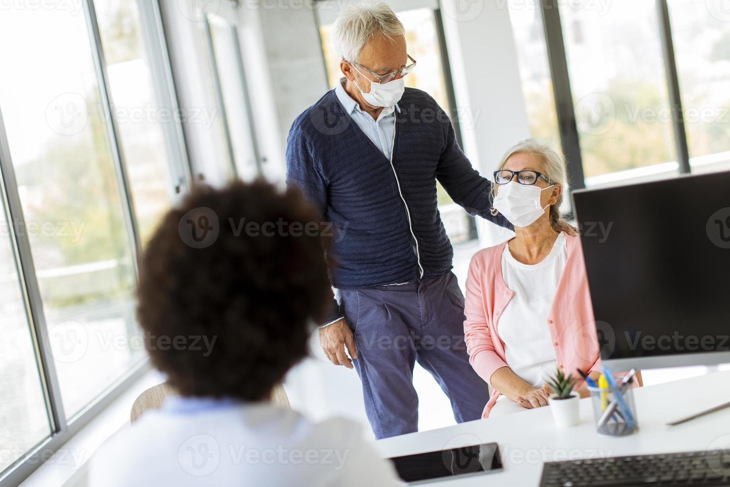 uomo maturo e moglie che si prendono a vicenda nell'ufficio del medico foto