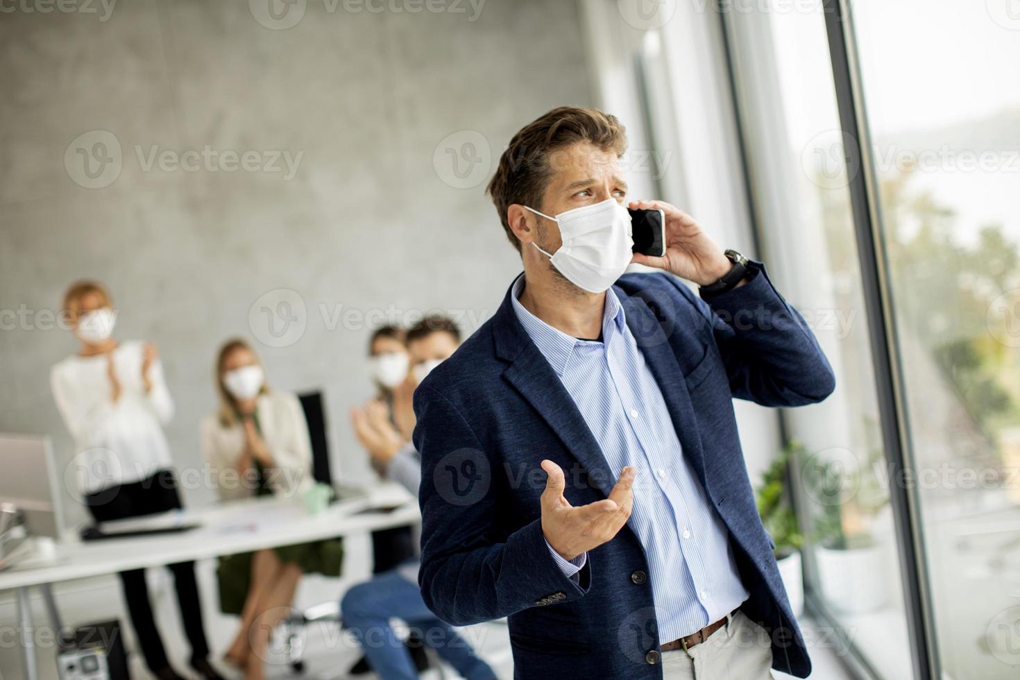 uomo mascherato sul telefono in ufficio foto