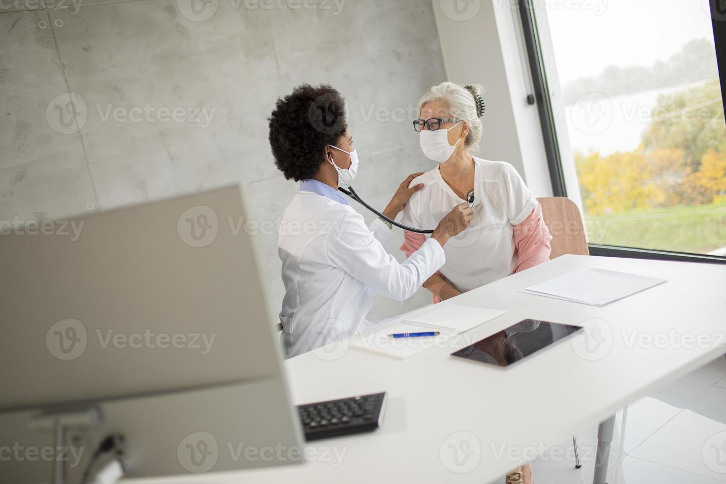 medico che ascolta il cuore della donna matura foto