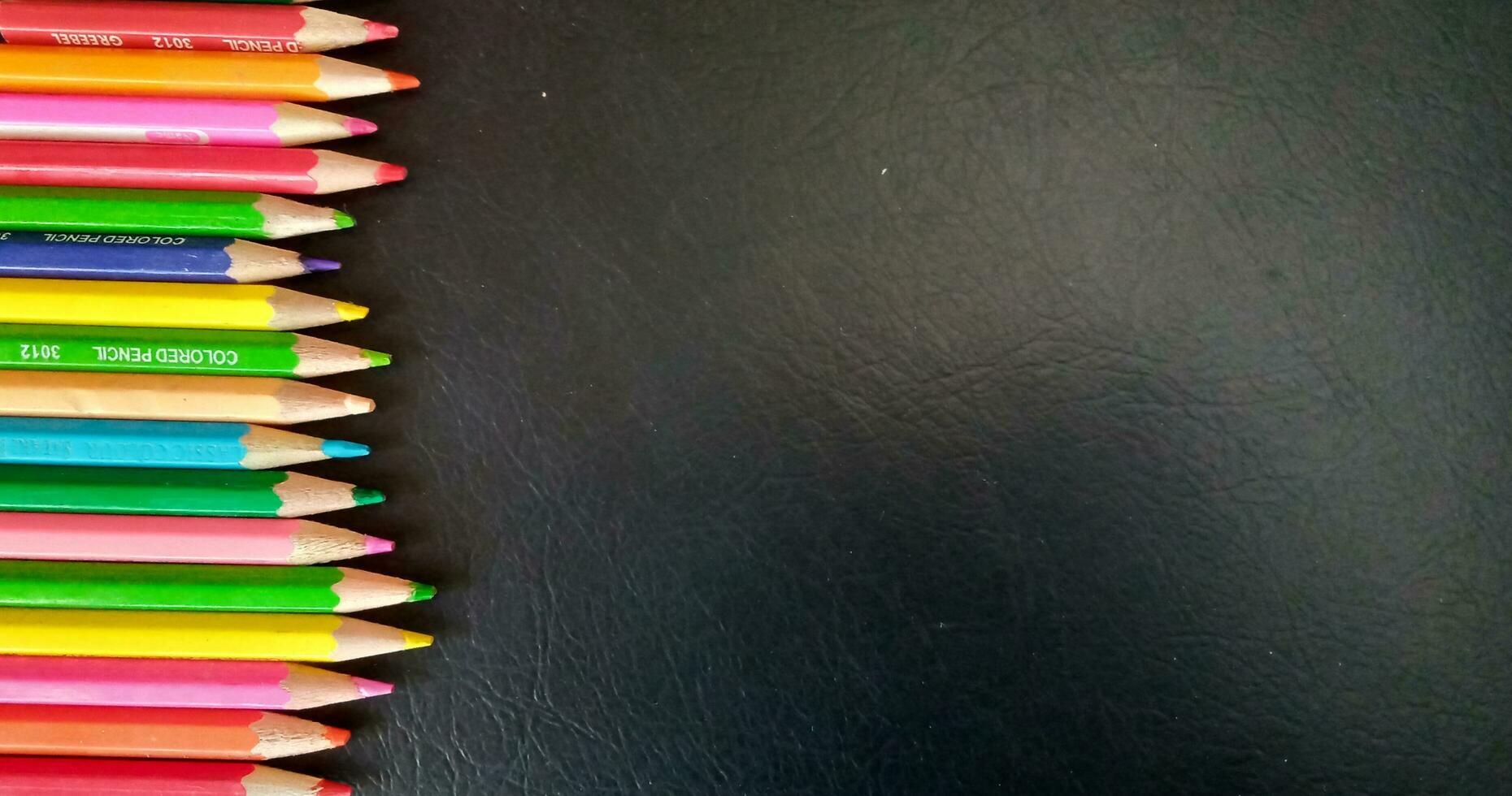 impostato di colorato matite su un' nero sfondo. adatto come un' sfondo per manifesti, banner o modelli relazionato per formazione scolastica. foto