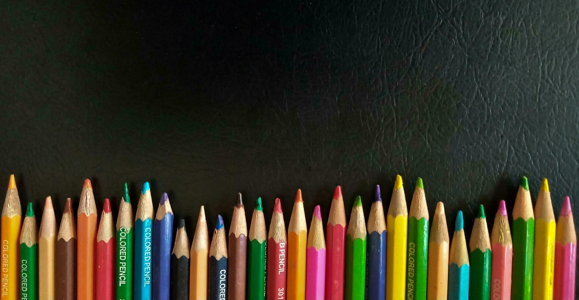 impostato di colorato matite su un' nero sfondo. adatto come un' sfondo per manifesti, banner o modelli relazionato per formazione scolastica. foto