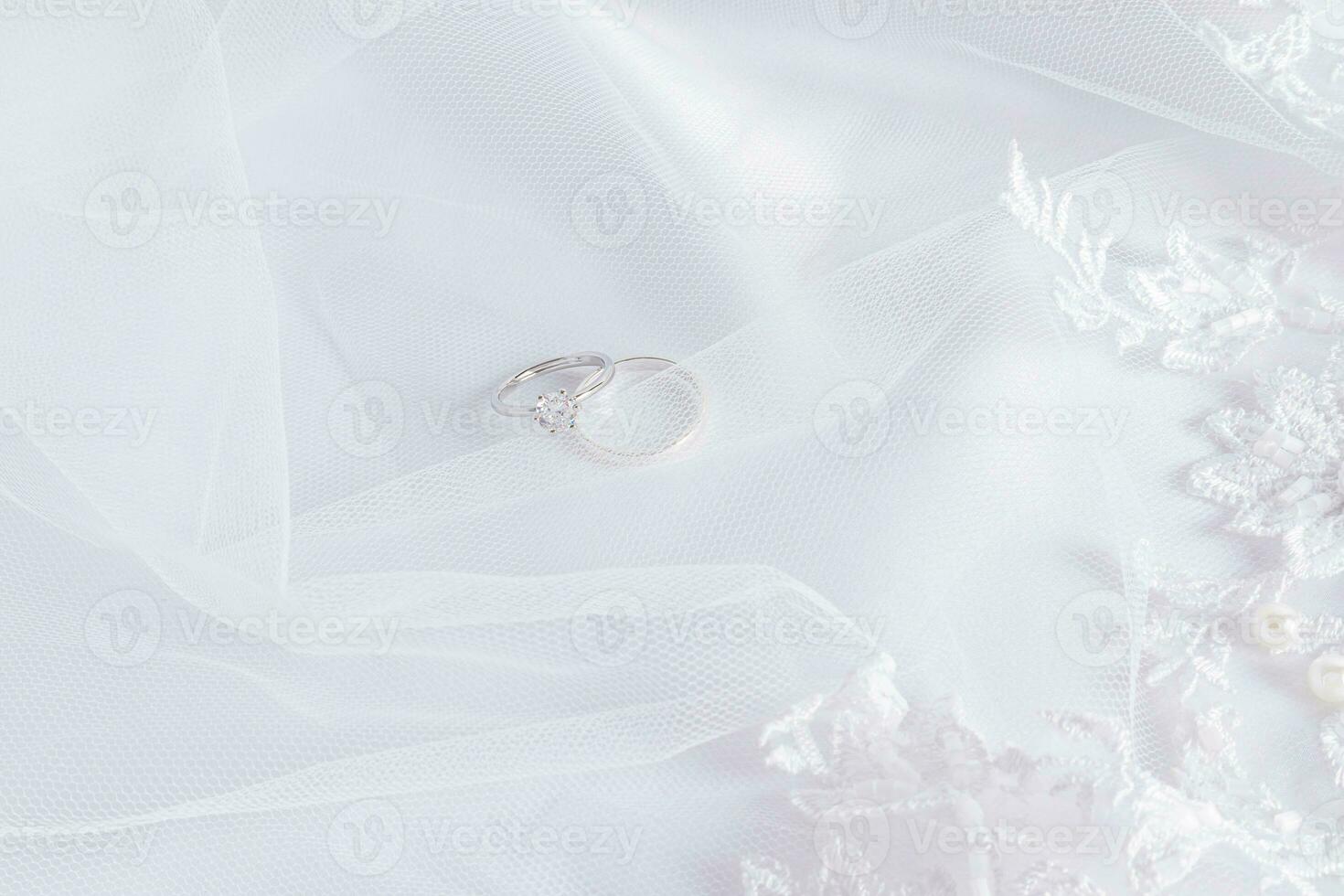 superiore Visualizza di Due diamante platino Fidanzamento anelli su un' bianca elegante raso sfondo con morbido onde e perle. nozze sfondo. foto