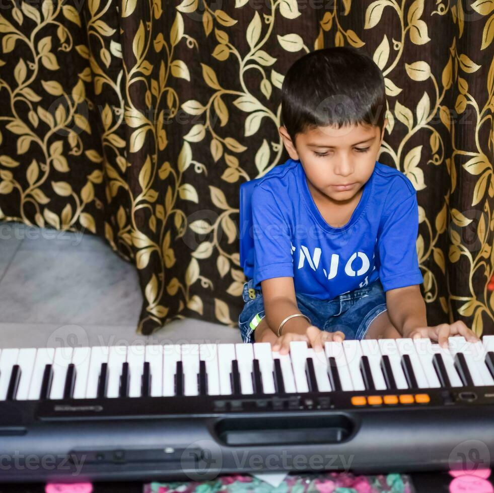 asiatico ragazzo giocando il sintetizzatore o pianoforte. carino poco ragazzo apprendimento Come per giocare pianoforte. del bambino mani su il tastiera interno. foto