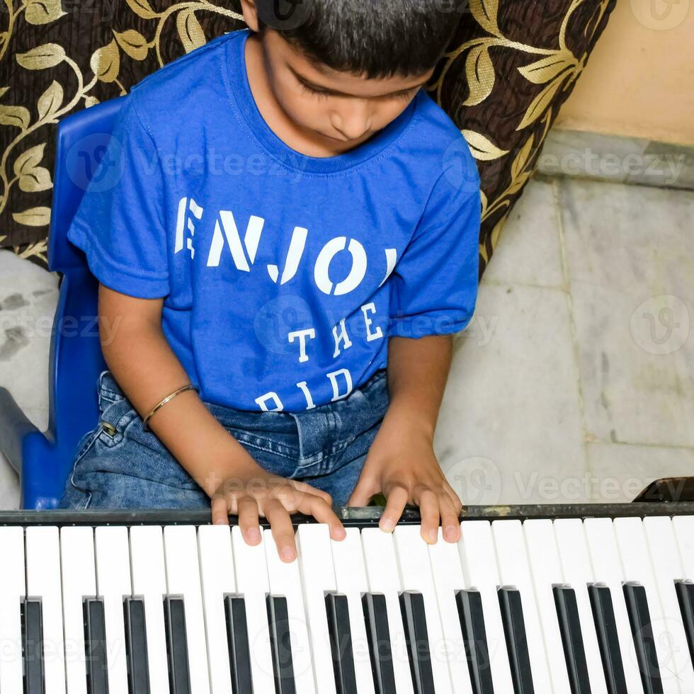 asiatico ragazzo giocando il sintetizzatore o pianoforte. carino poco ragazzo apprendimento Come per giocare pianoforte. del bambino mani su il tastiera interno. foto