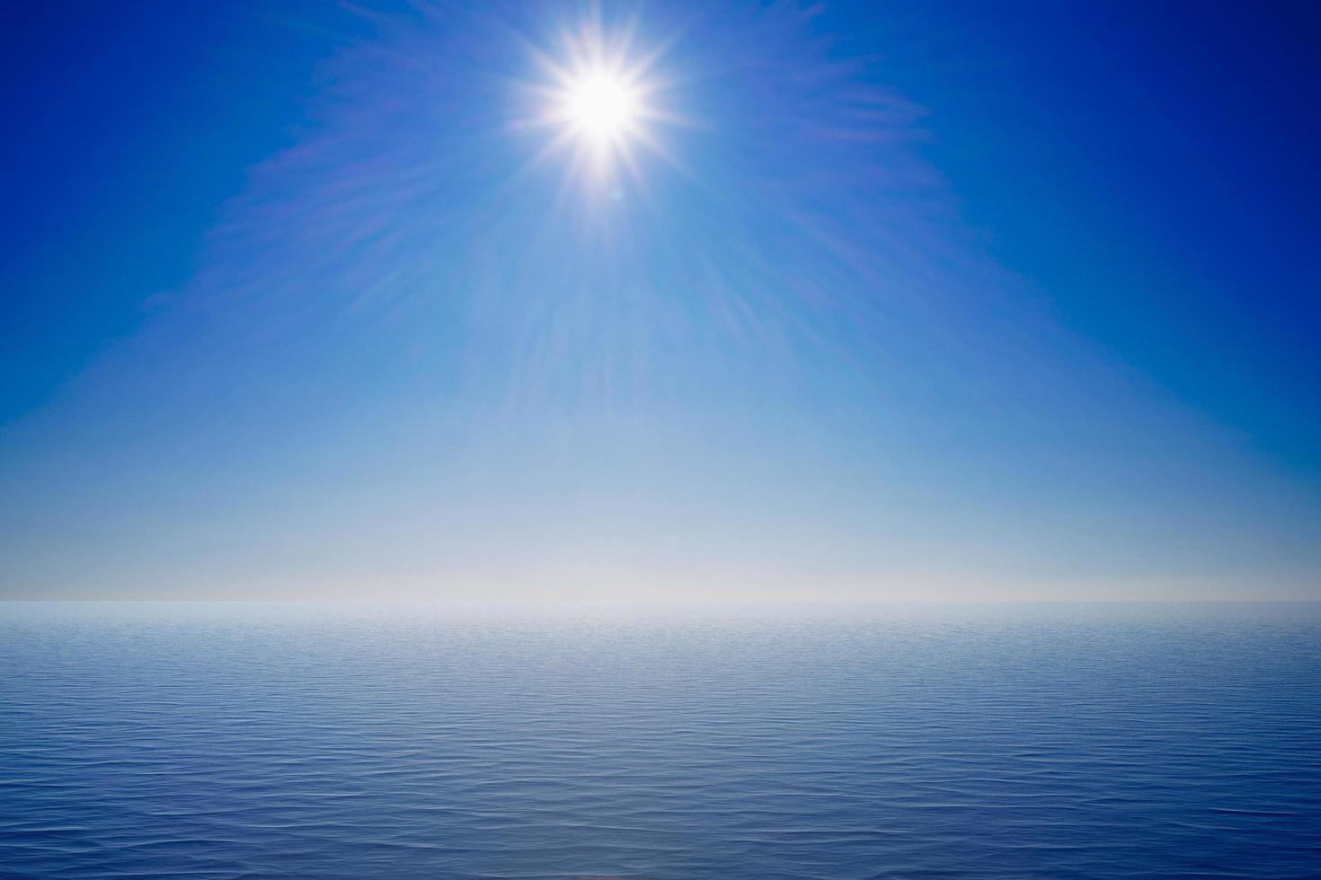 vista sul mare con un sole splendente su un cielo blu foto