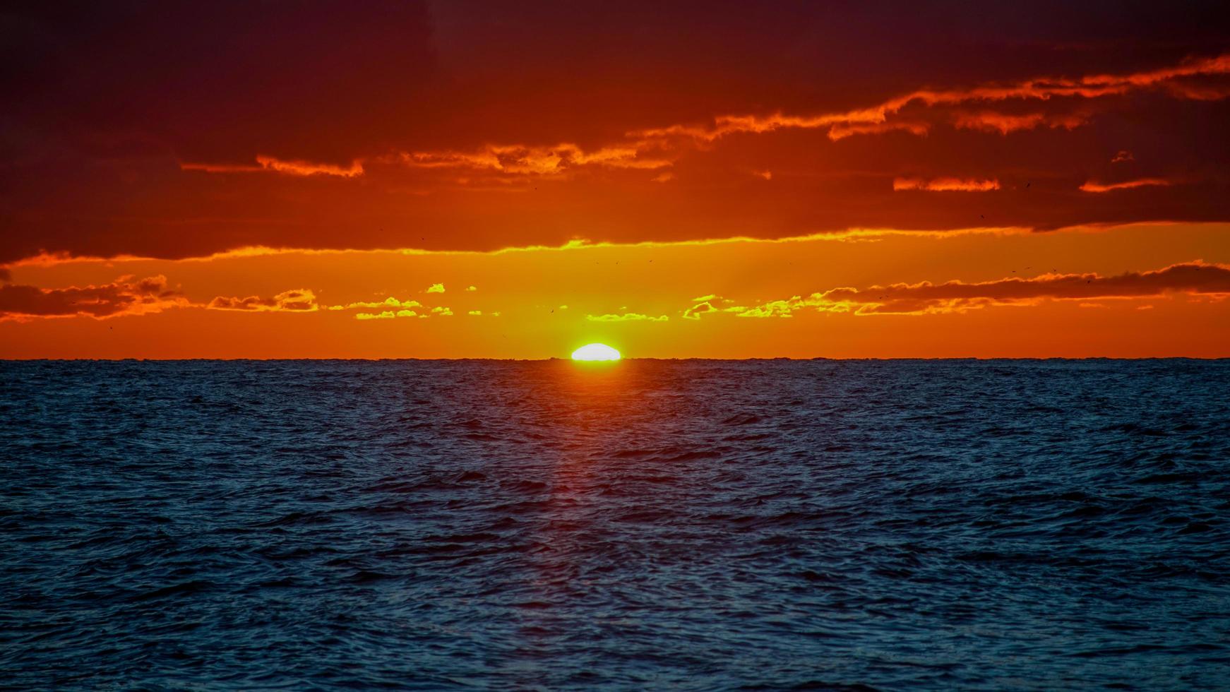 drammatico tramonto infuocato sul paesaggio del mare foto