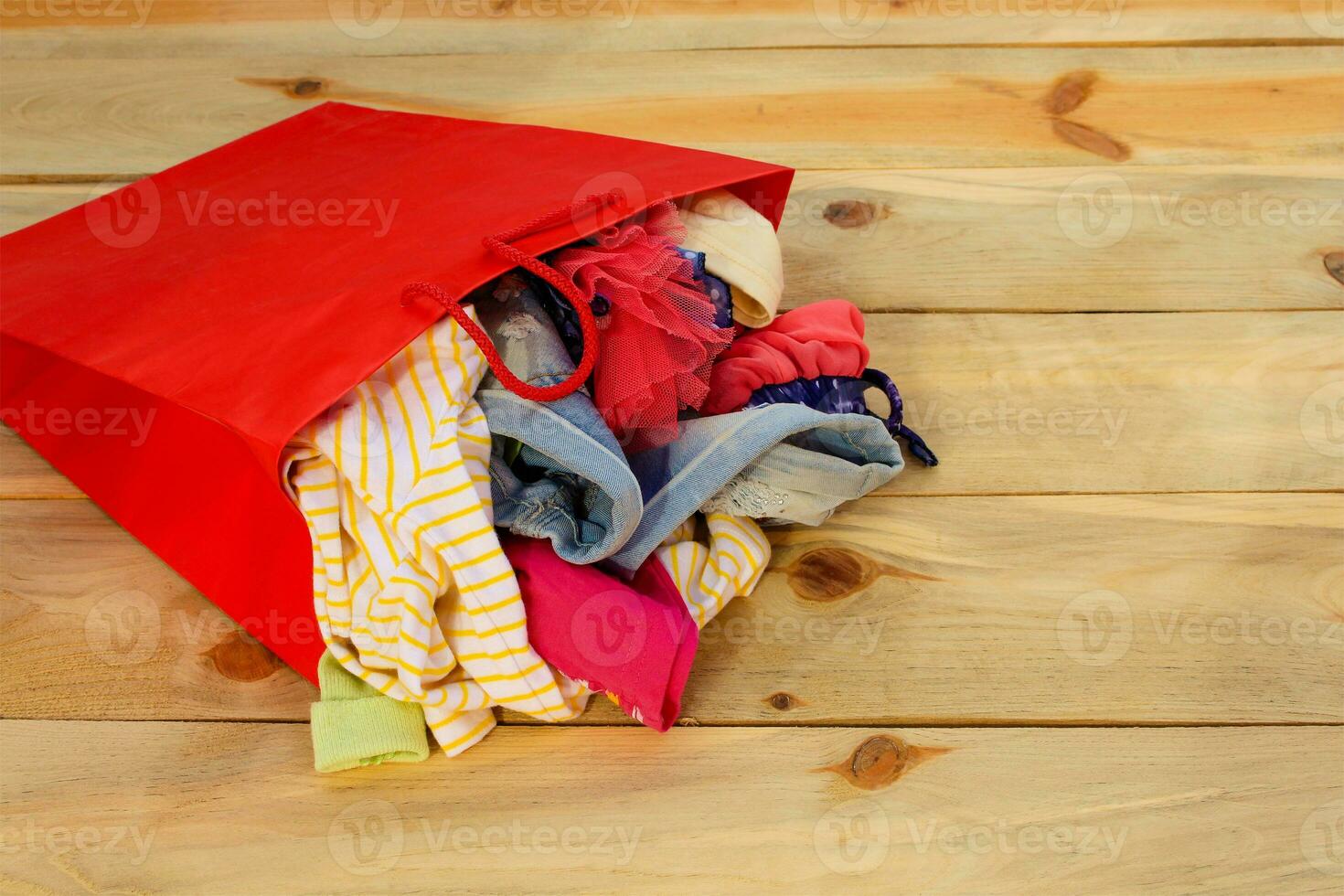 Da donna capi di abbigliamento cascate su di carta shopping borse su di legno sfondo. foto