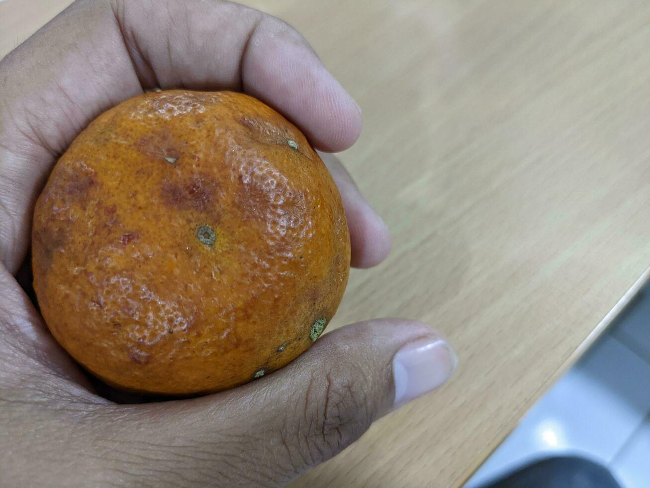 marcio arance hold con mano e al di sopra di il di legno tavoli. il foto è adatto per uso per frutta sfondo e venditore pubblicità.