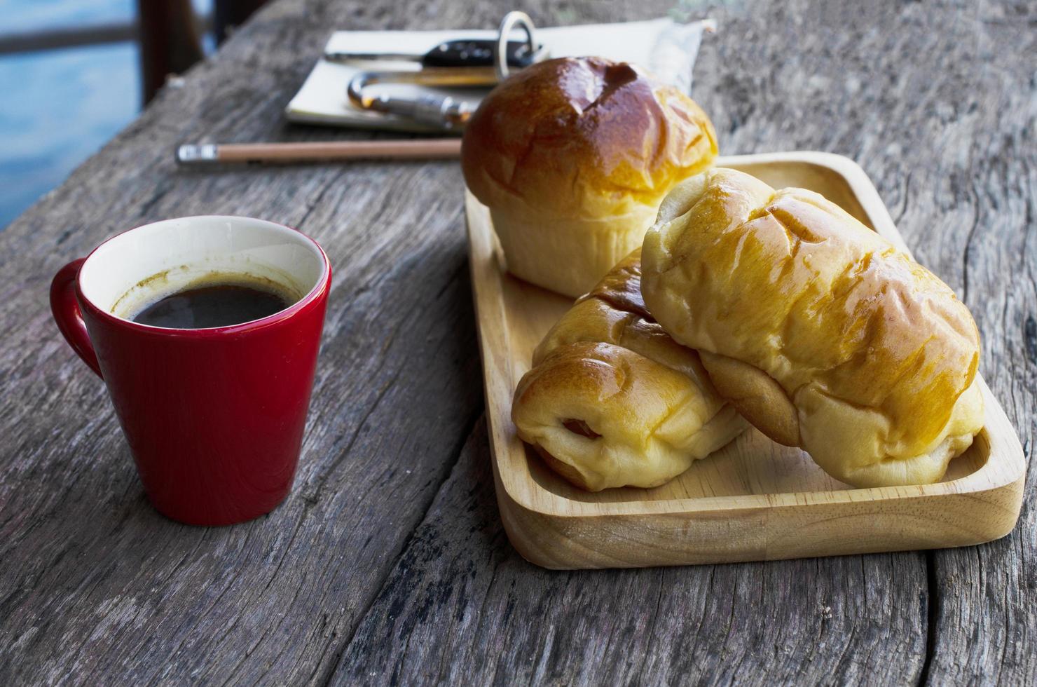 Close up rosso tazza di caffè e pane panino fatto in casa sul fondo della tavola in legno foto
