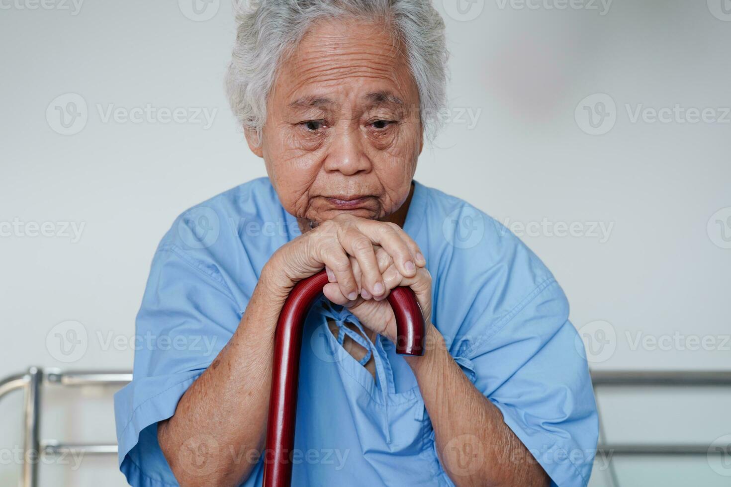 asiatico anziano invalidità donna paziente Tenere a piedi bastone nel rugosa mano a Ospedale. foto