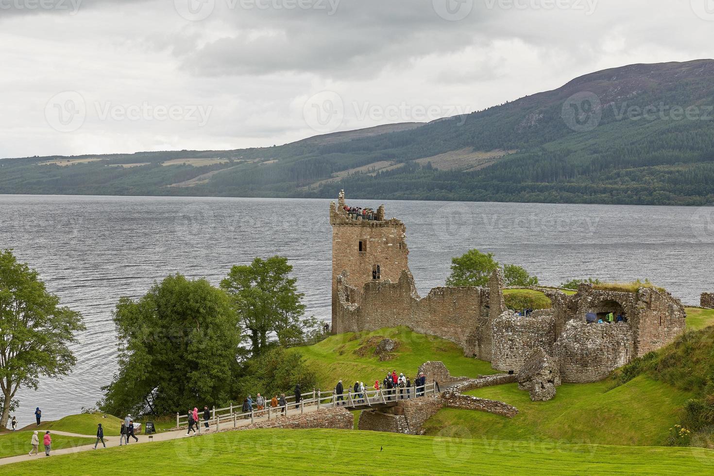 Le persone che si godono la visita al castello di Urquhart sulle rive di Loch Ness in Scozia foto