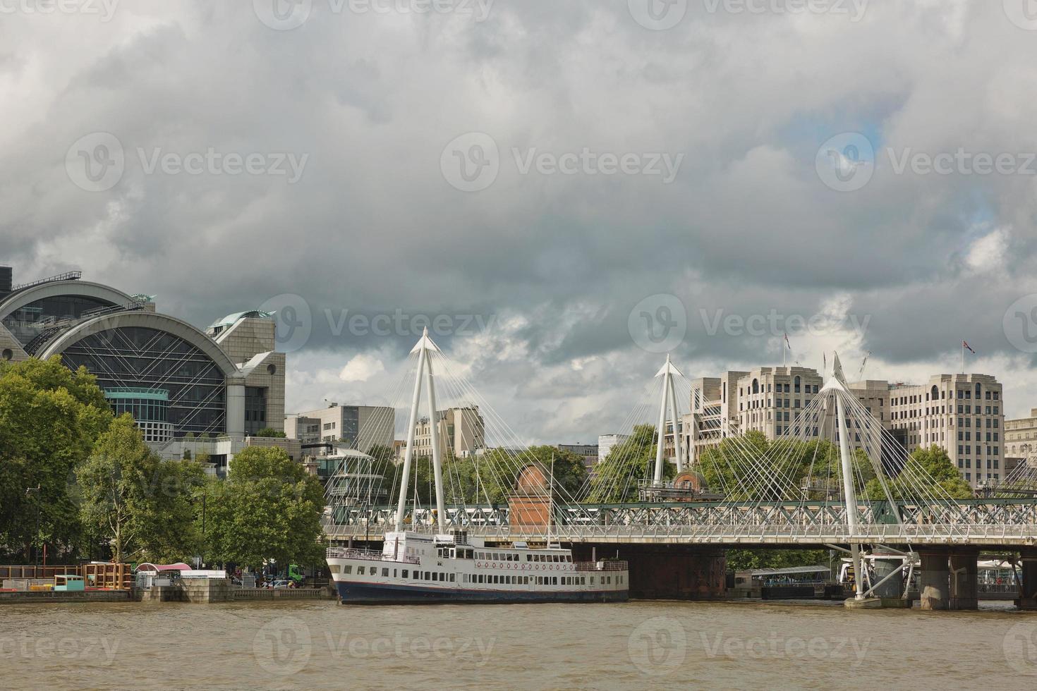 Vista dei ponti del giubileo d'oro e la stazione di Charing Cross dalla riva sud del fiume Tamigi a Londra in una torbida giornata estiva foto