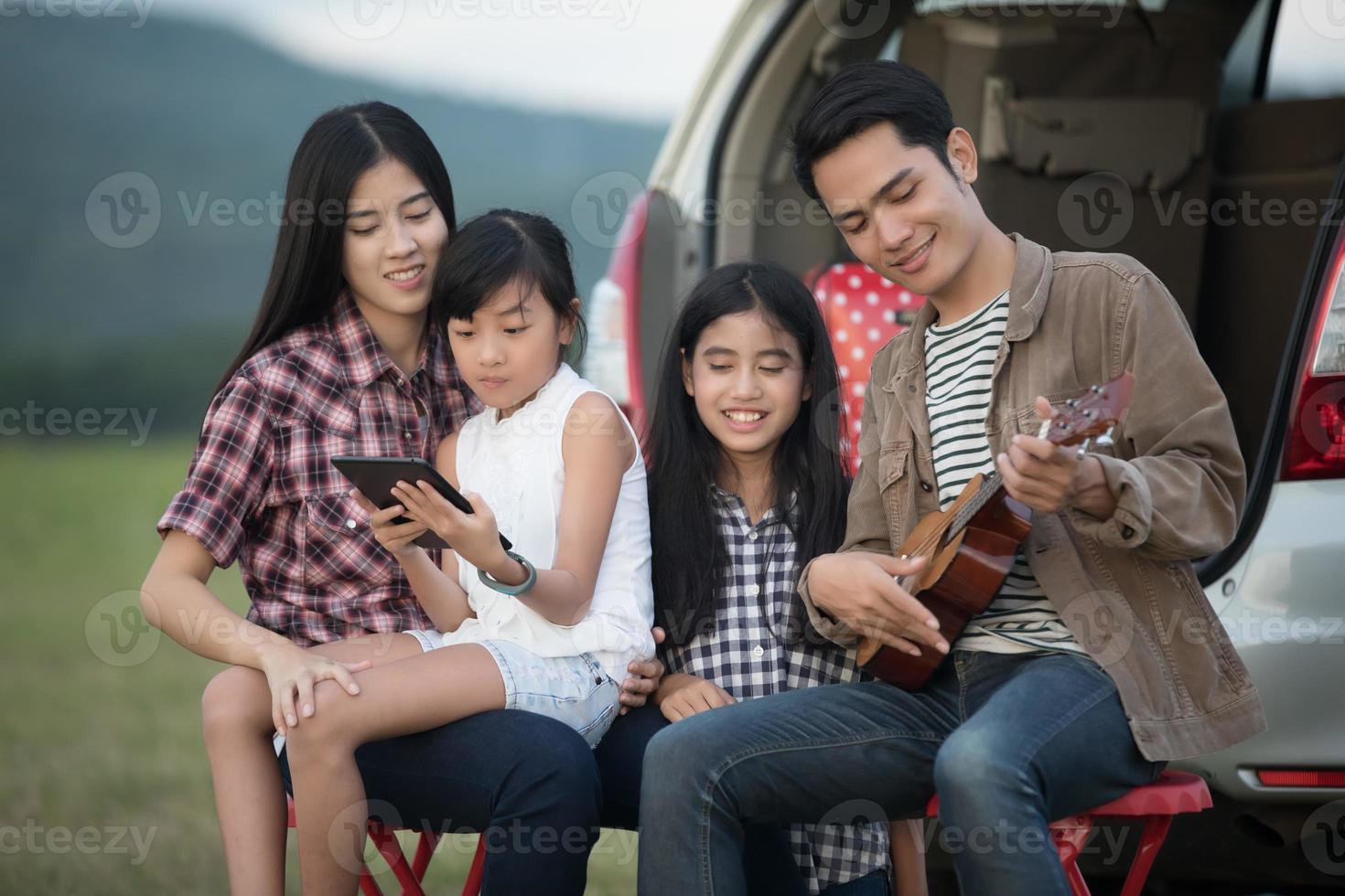 famiglia seduta fuori dall'auto che suona l'ukulele foto