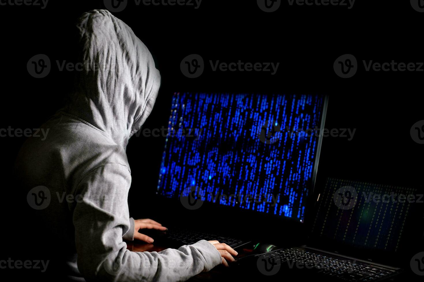 donne hacker irrompe nei server di dati del governo e infetta il loro sistema con un virus nel suo nascondiglio, atmosfera blu scuro, donna incappucciata che utilizza laptop con sfondo di codice binario, concetto di malware foto