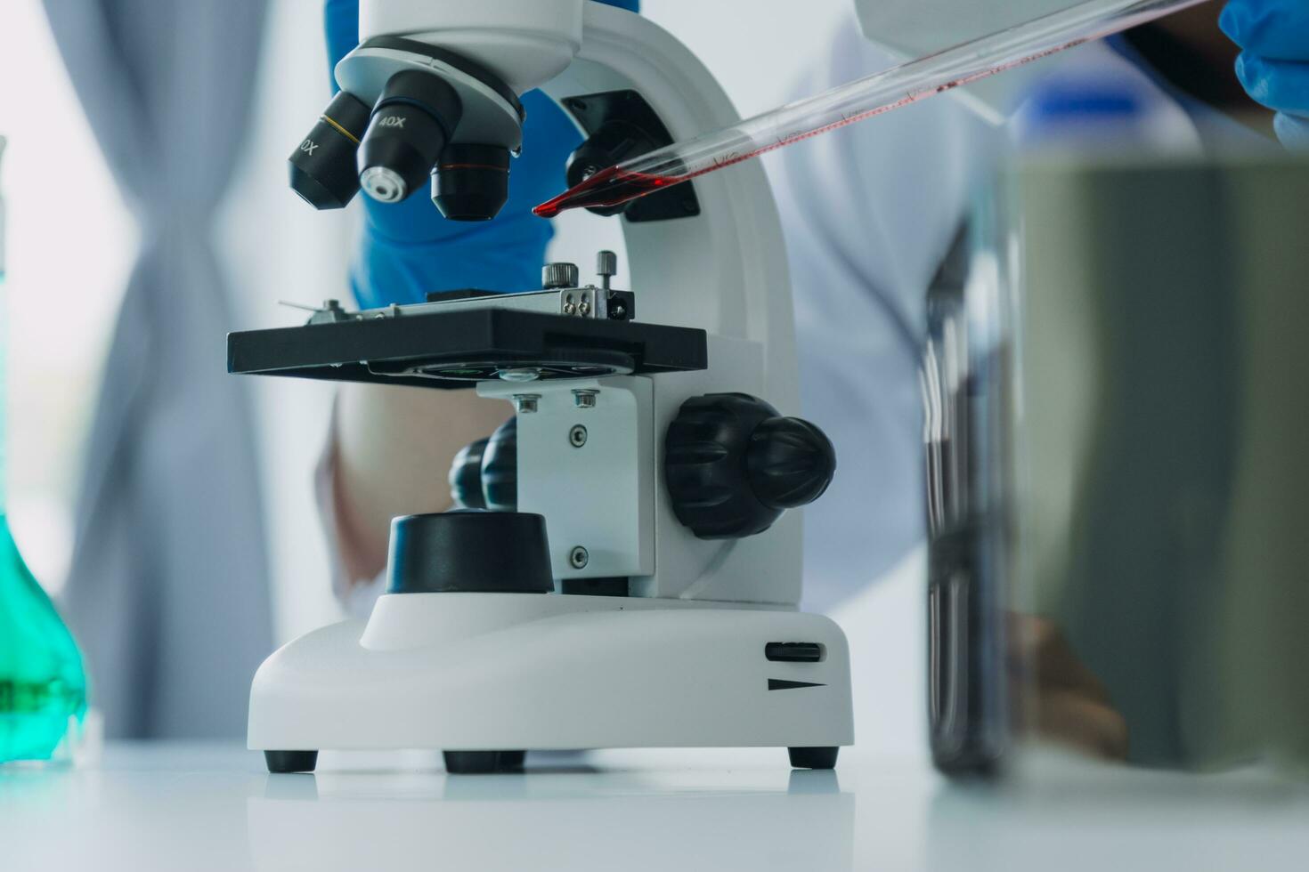 medico o scientifico ricercatore ricercando e sperimentando multicolore soluzione, fiala e microscopio nel il laboratorio o nel il laboratorio di indossare blu guanti e bianca capi di abbigliamento completamente. foto