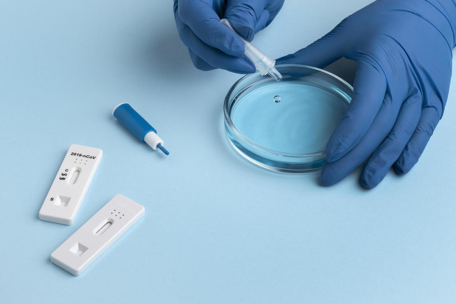 mano con guanti protettivi facendo un test covid con una capsula di Petri foto